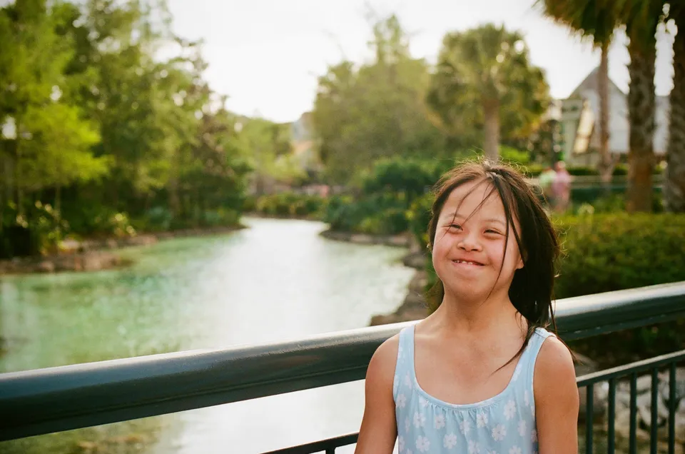 A smiling person beside a railing overlooking a tree lined waterway in Orlando