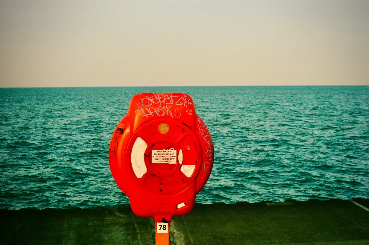 A bright red life ring beside the turquoise water of Lake Michigan in Chicago