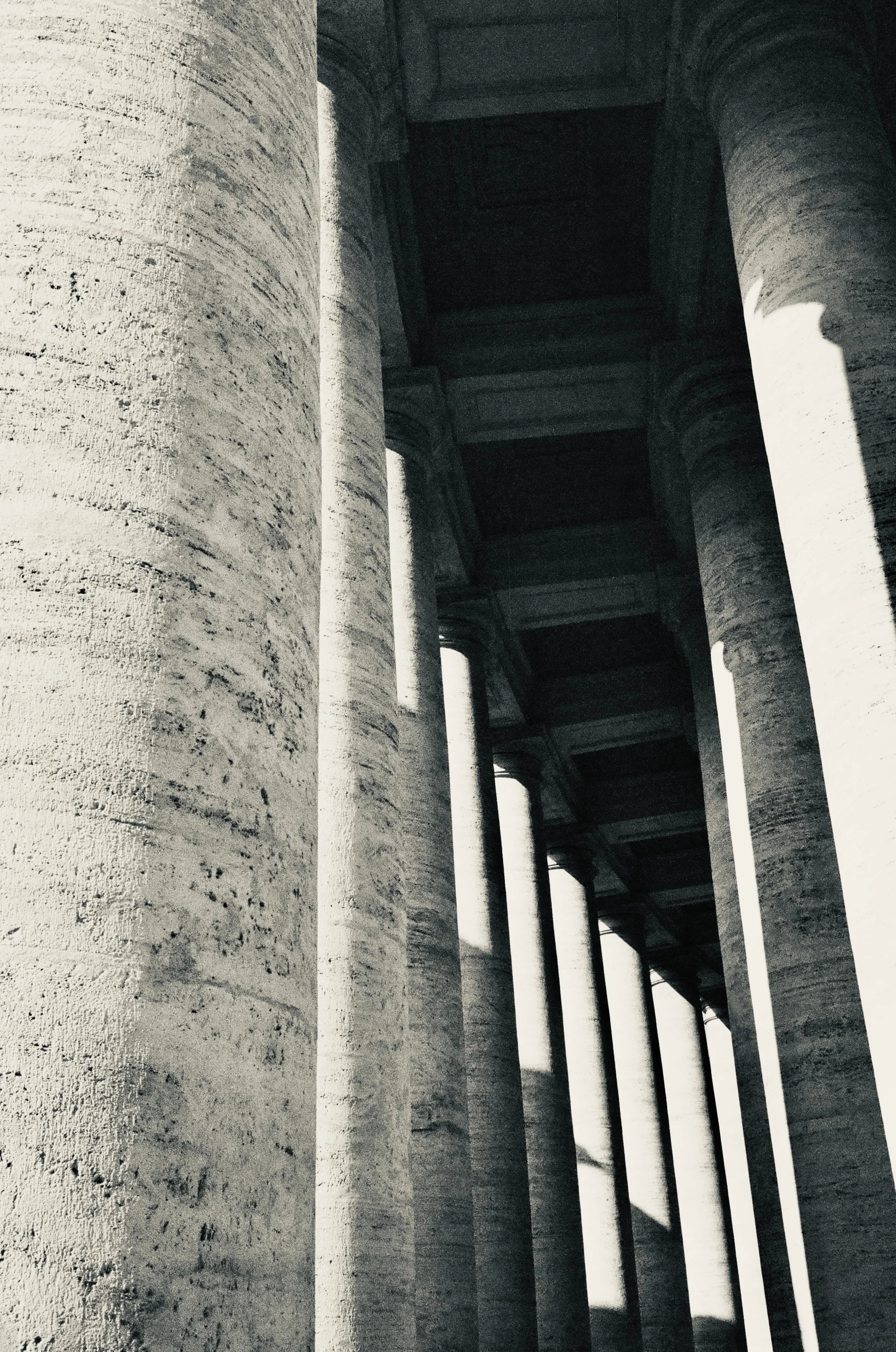 A long row of stone columns receding into deep shadow in Rome