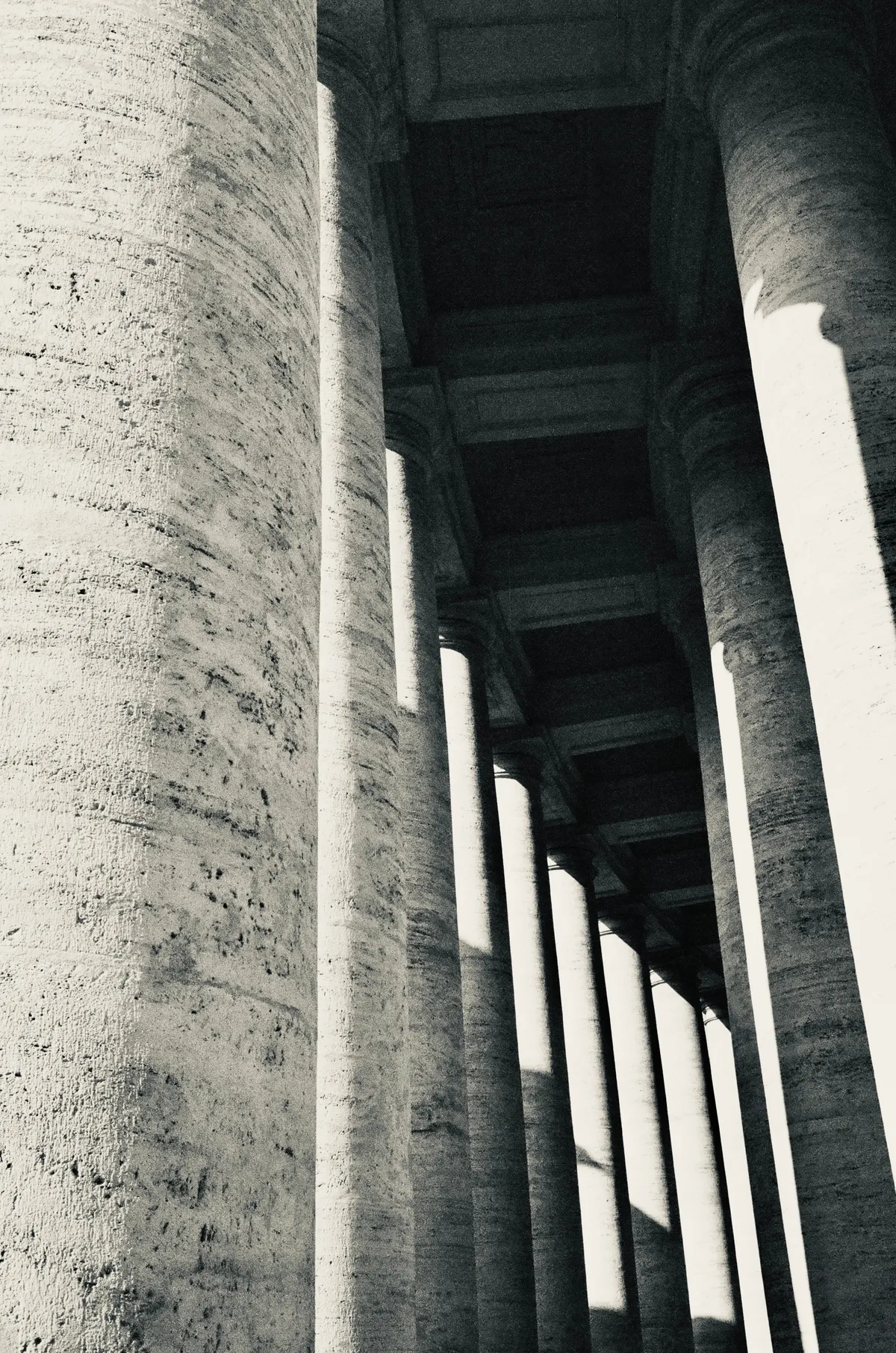 A long row of stone columns receding into deep shadow in Rome
