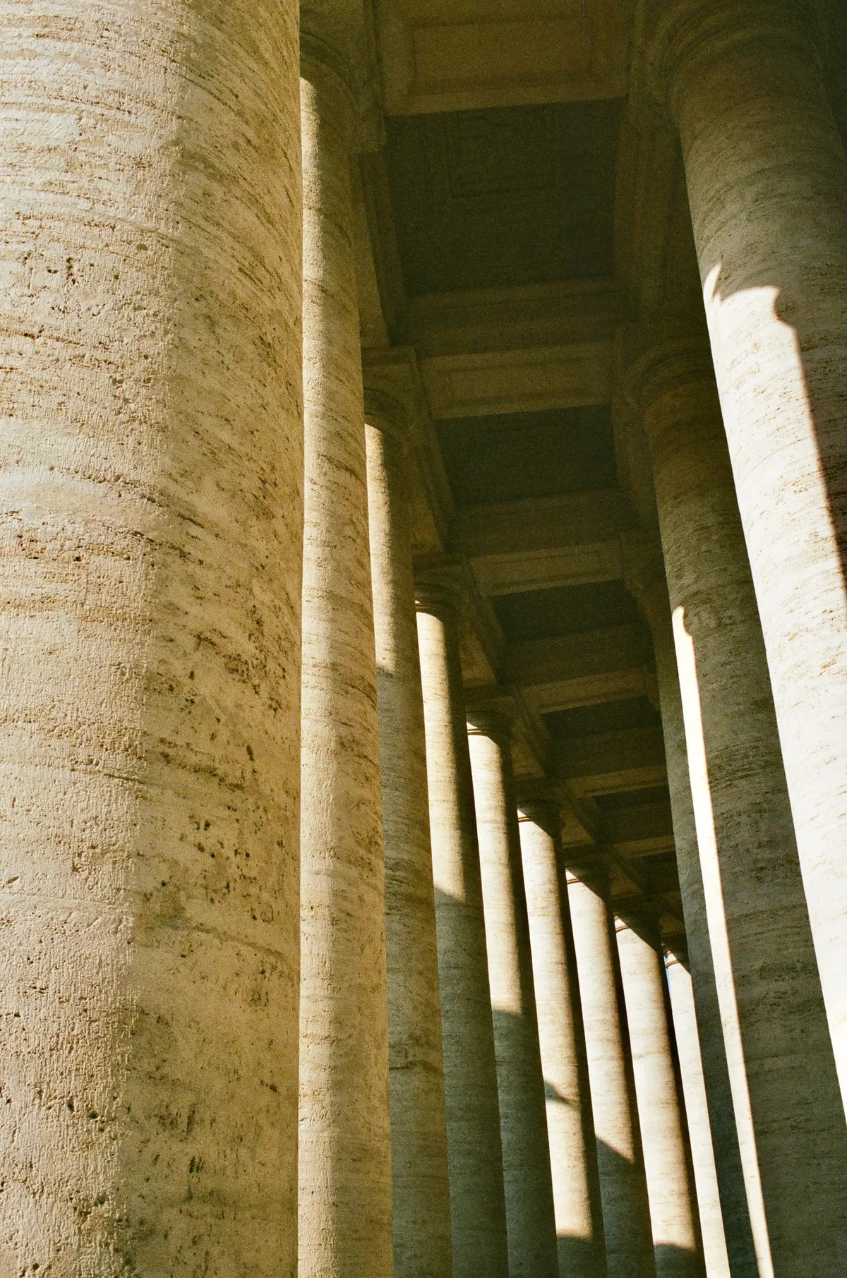 Sunlit stone columns framing a shaded passage in Rome