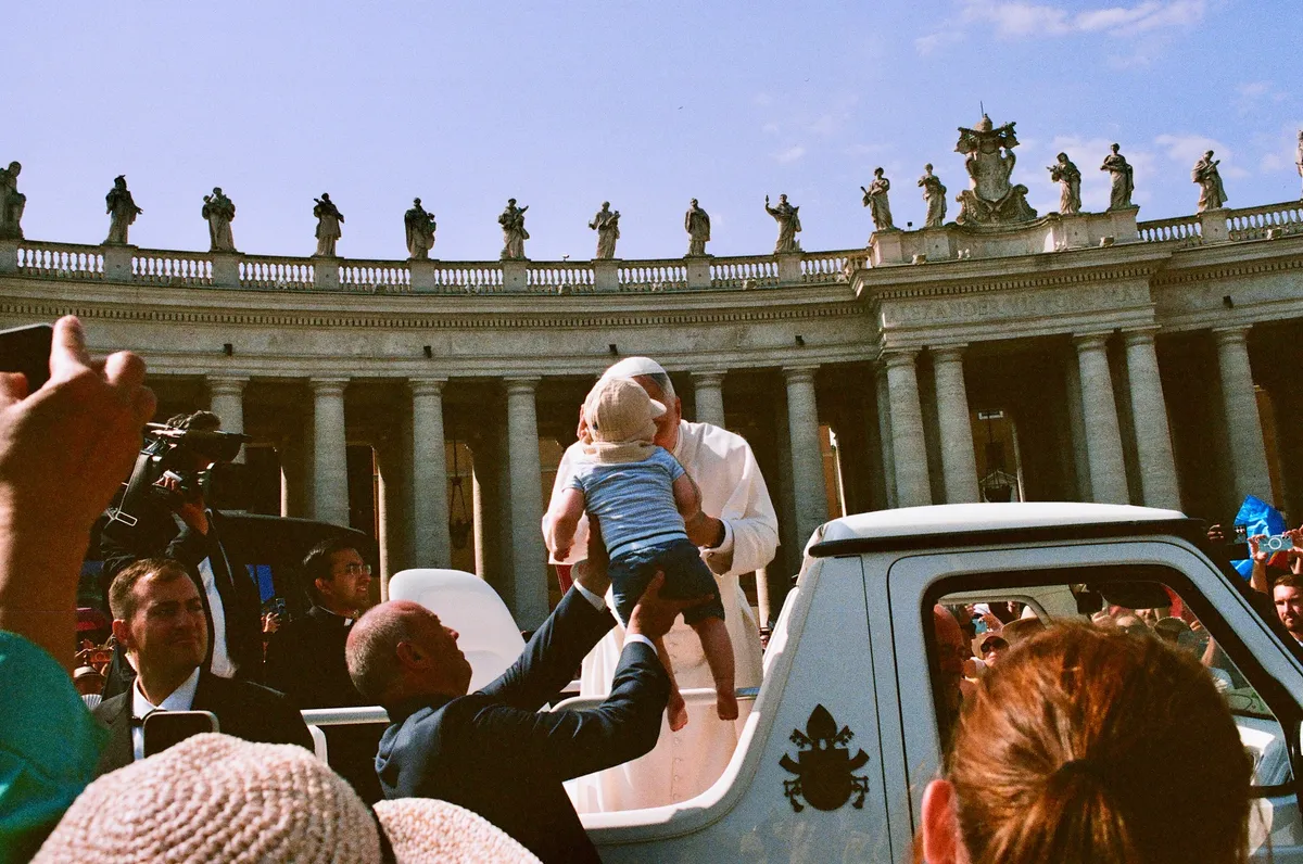 People reaching toward the pope as his open vehicle passes in Rome