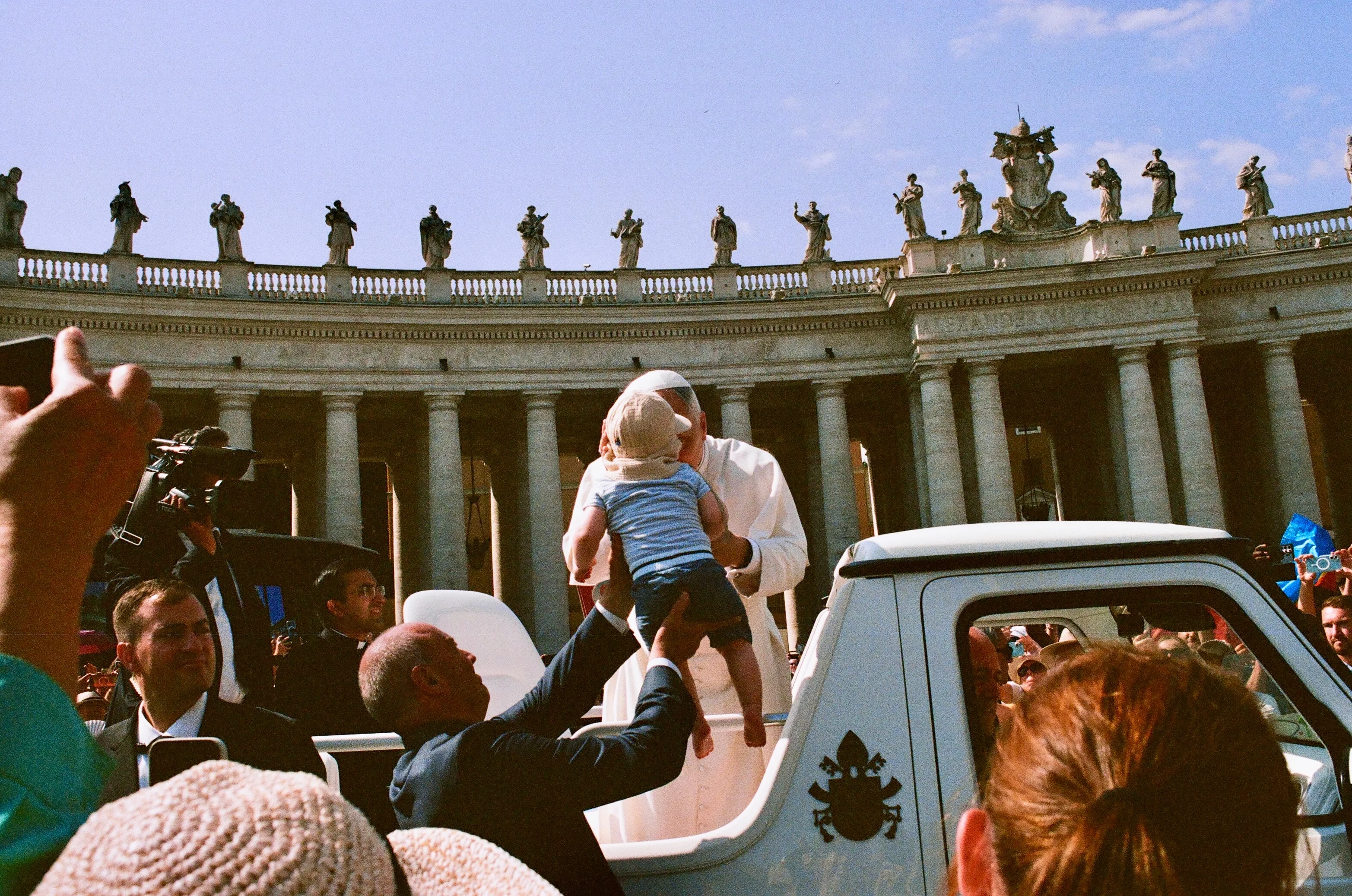 People reaching toward the pope as his open vehicle passes in Rome