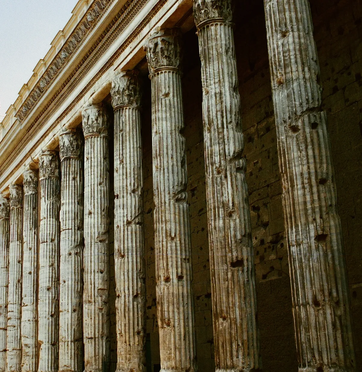 Tall weathered columns and carved stonework seen from below in Rome
