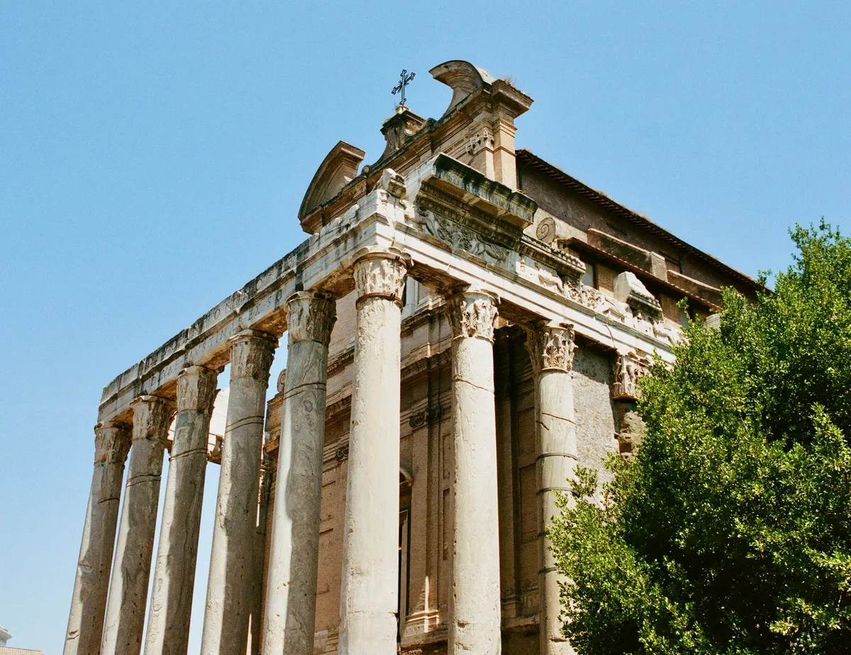 Ancient temple columns rising against a clear blue sky in Rome