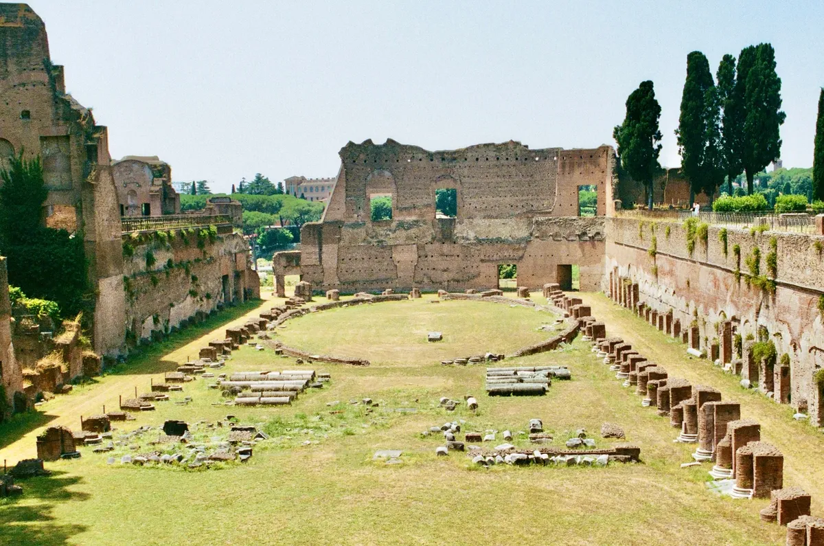 A long grassy courtyard surrounded by ancient brick ruins in Rome