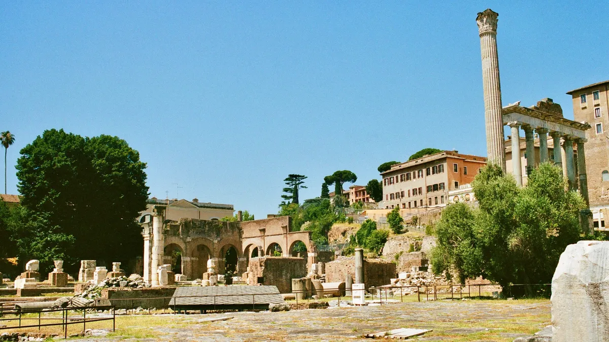Ancient ruins and a tall stone column beneath a blue sky in Rome