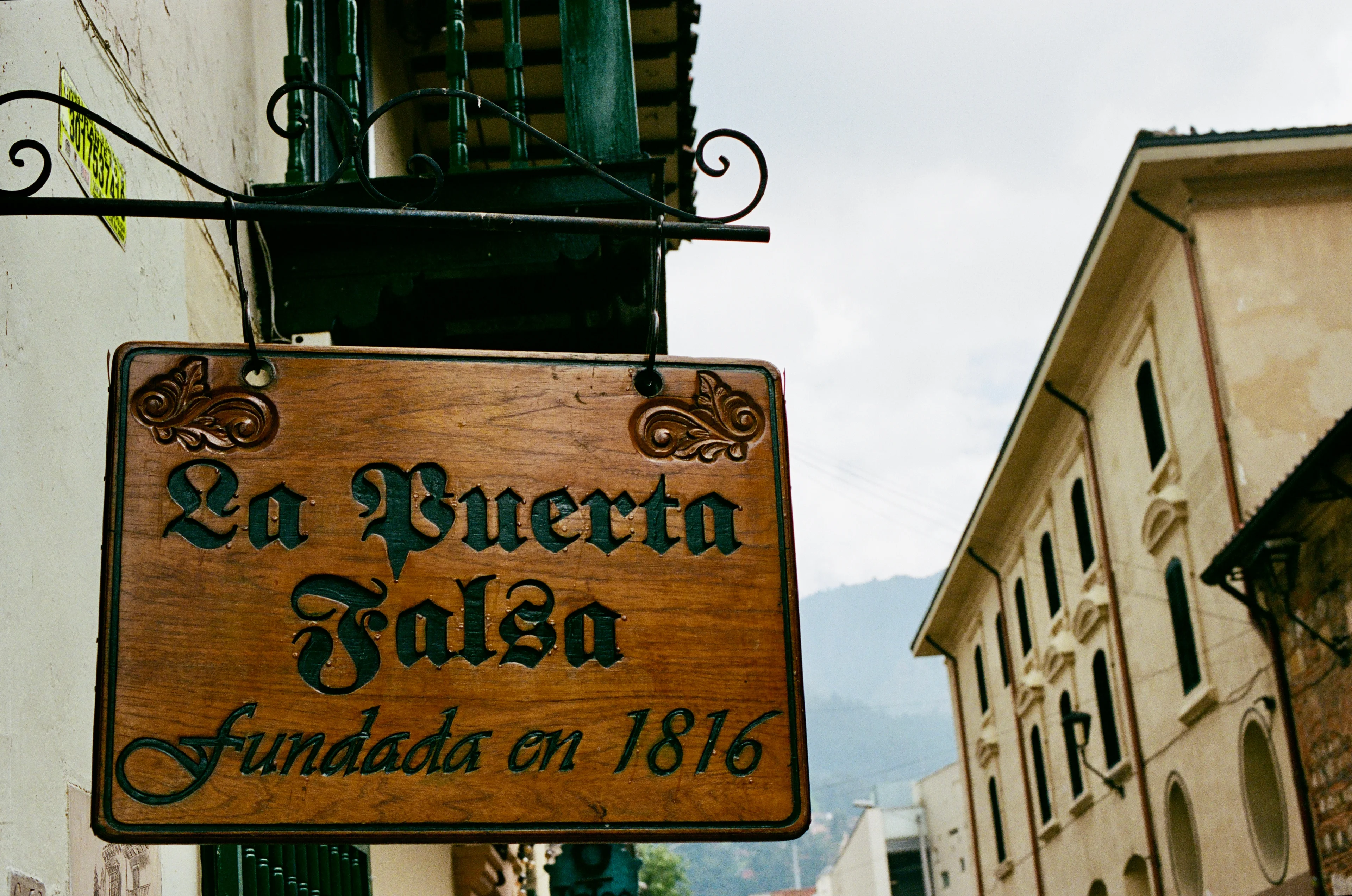 The hanging La Puerta Falsa sign above a narrow street in Bogota