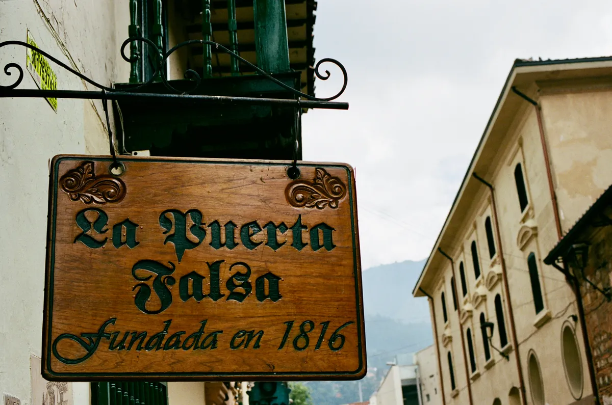 The hanging La Puerta Falsa sign above a narrow street in Bogota