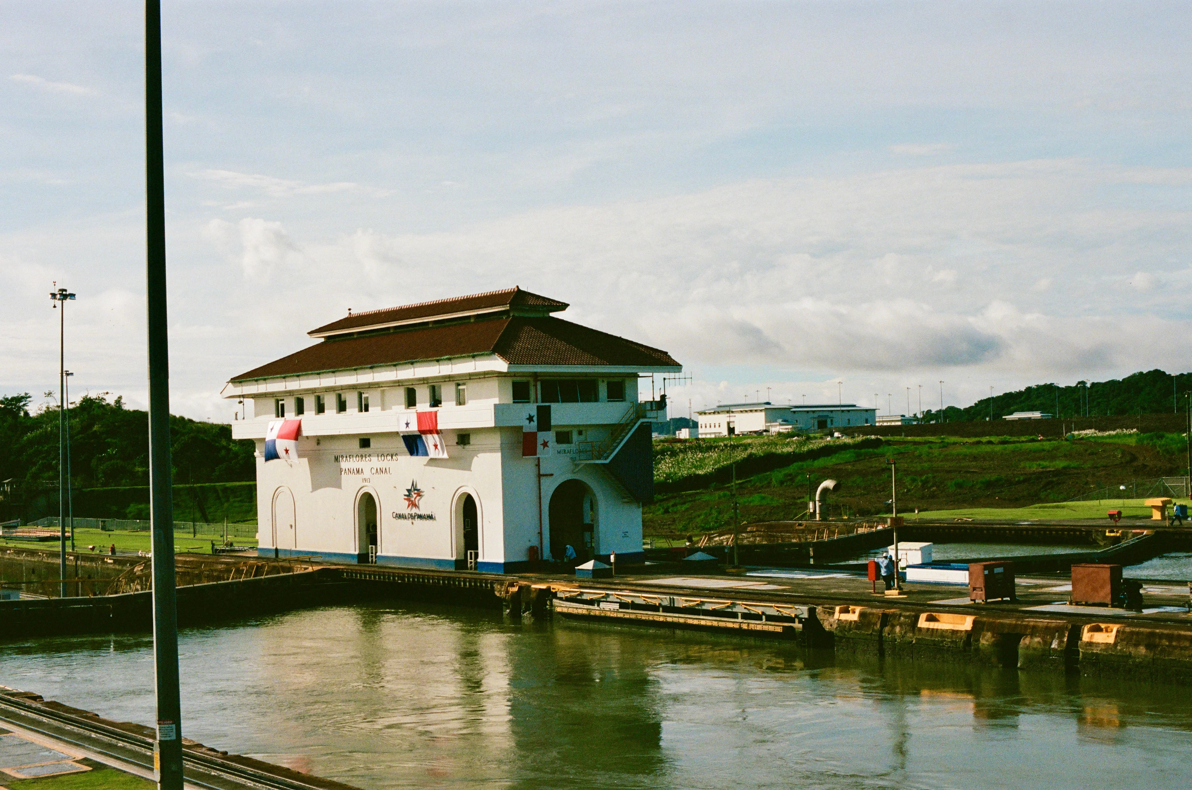 A small canal building beside the water under an overcast sky in Panama City