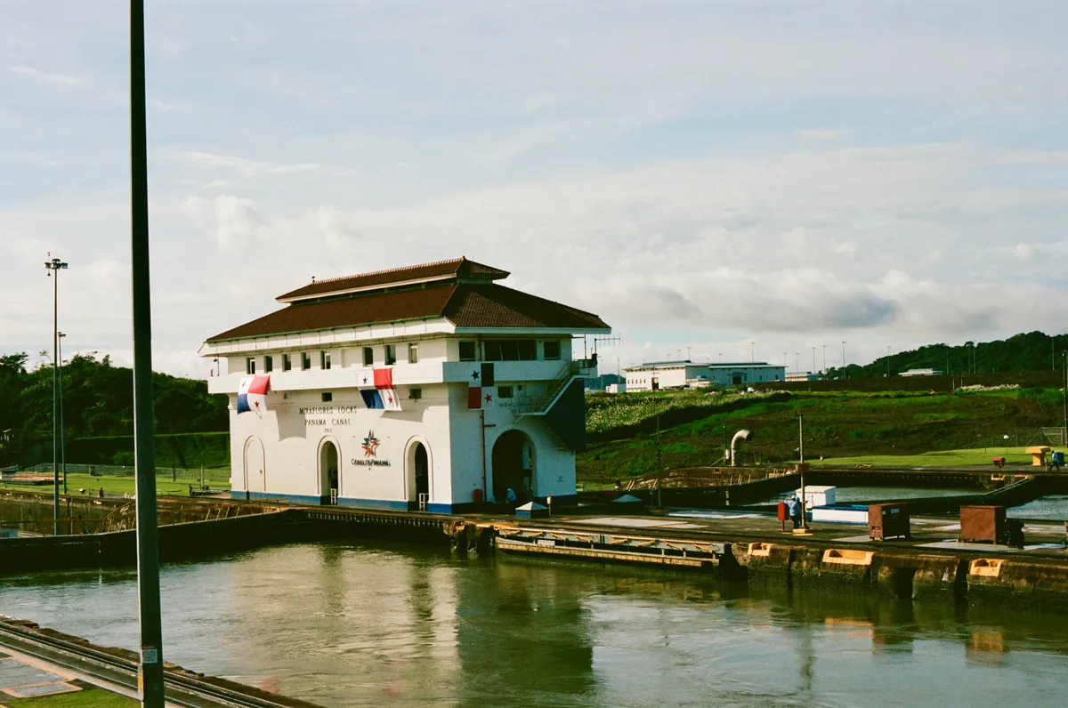 A small canal building beside the water under an overcast sky in Panama City