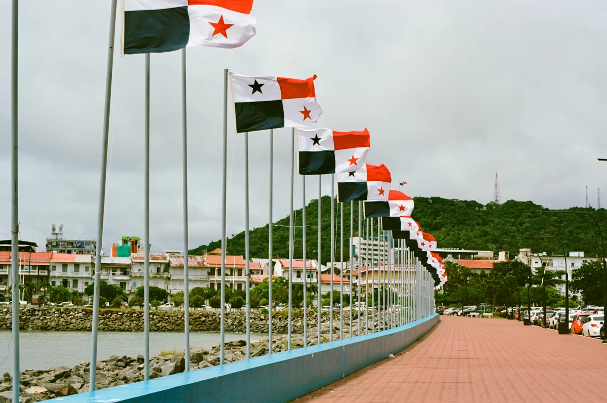 A curving waterfront walkway lined with national flags in Panama City