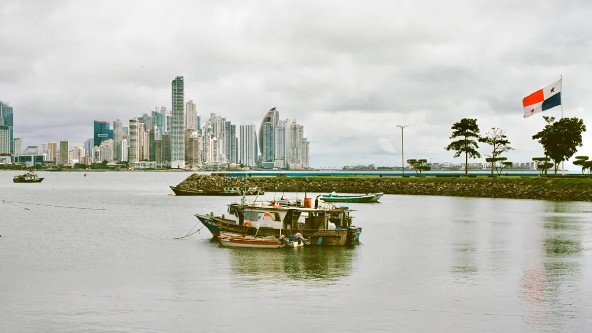 A boat on calm water with the city skyline in the distance in Panama City